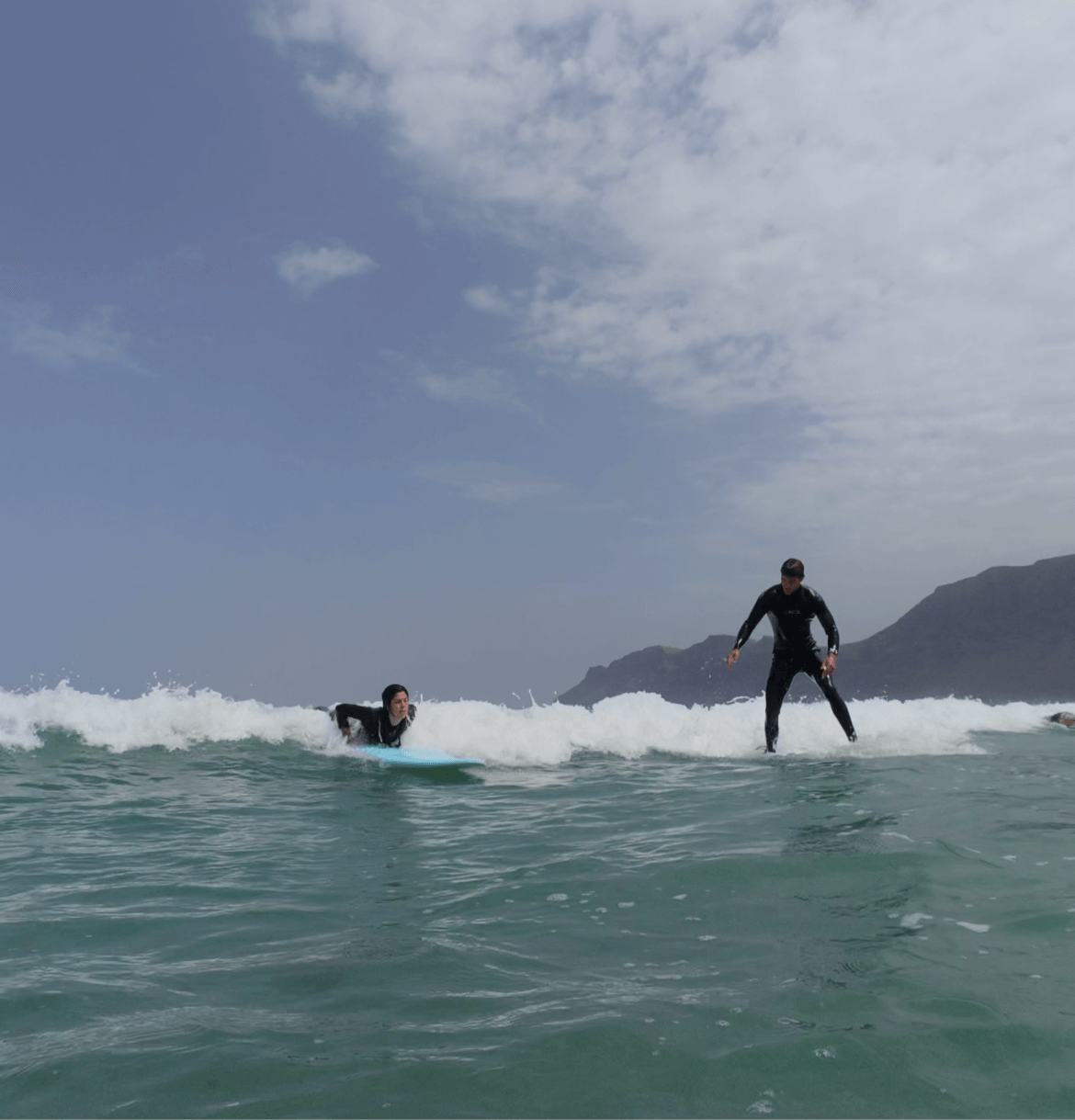 Private surf lesson for two at Famara Beach, Lanzarote with instructor coaching beginner surfers on waves