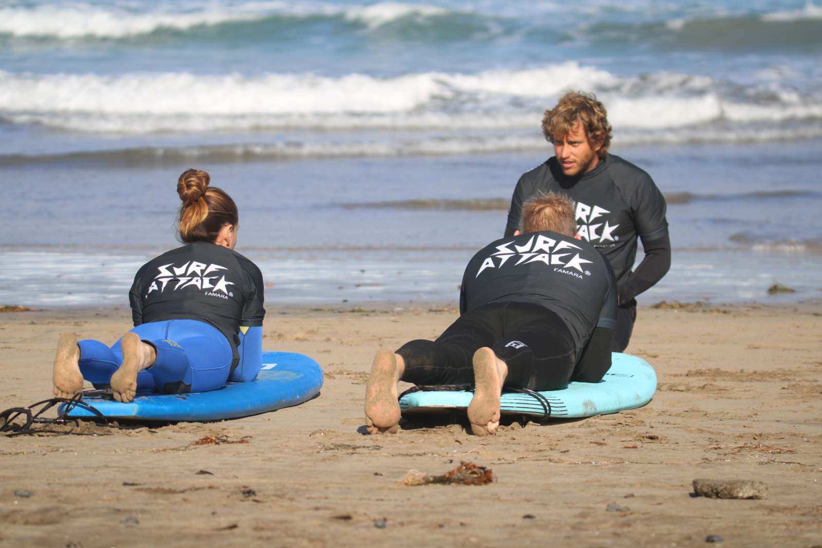 Two surfers receiving a private surf lesson with an instructor on Famara Beach, Lanzarote