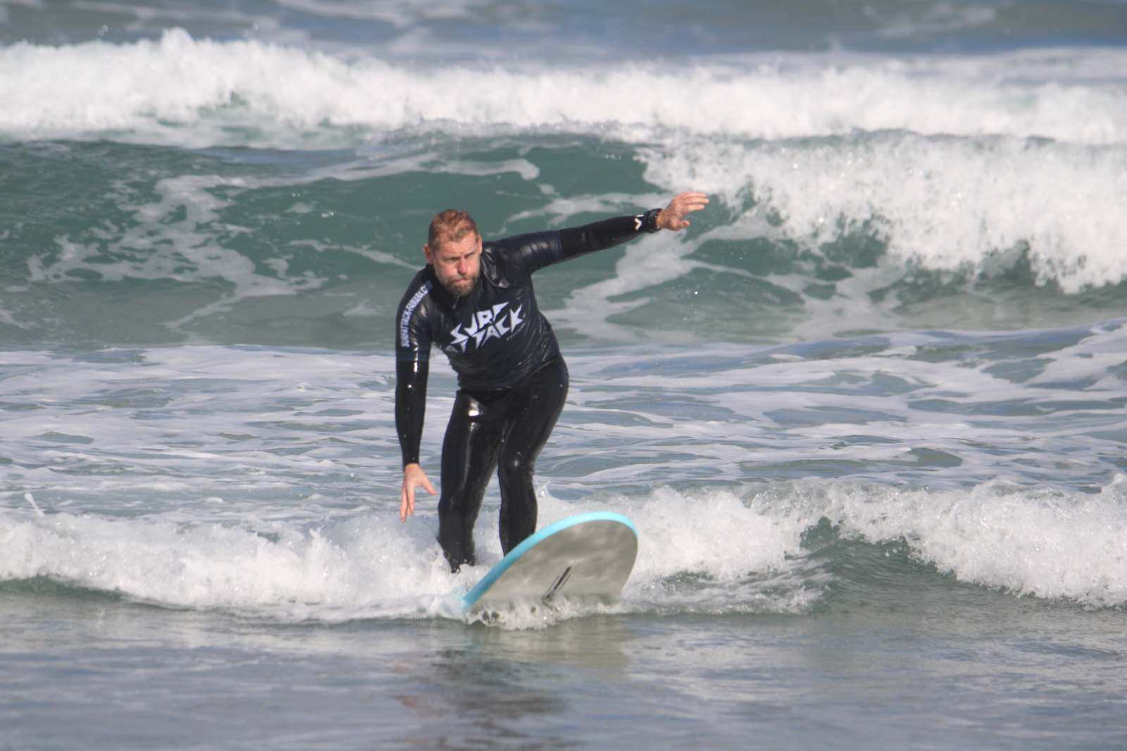 Surfer taking a lesson on a wave at Famara Beach during a 1-day surf course with small group coaching in Lanzarote