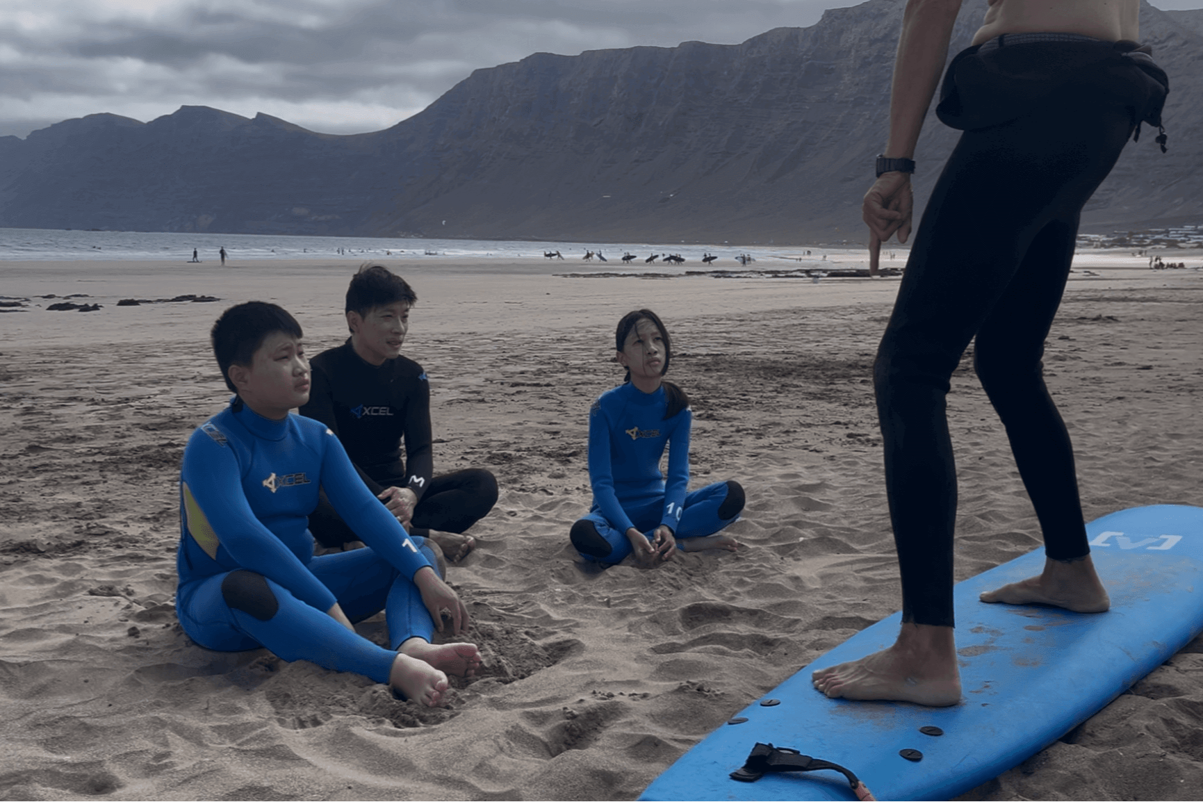 Small group surf lesson on Famara Beach, Lanzarote with instructor and students in wetsuits