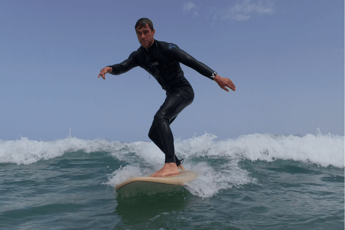 Surfer in wetsuit riding small wave during 1/2 day small group surf lesson at Famara Beach Lanzarote