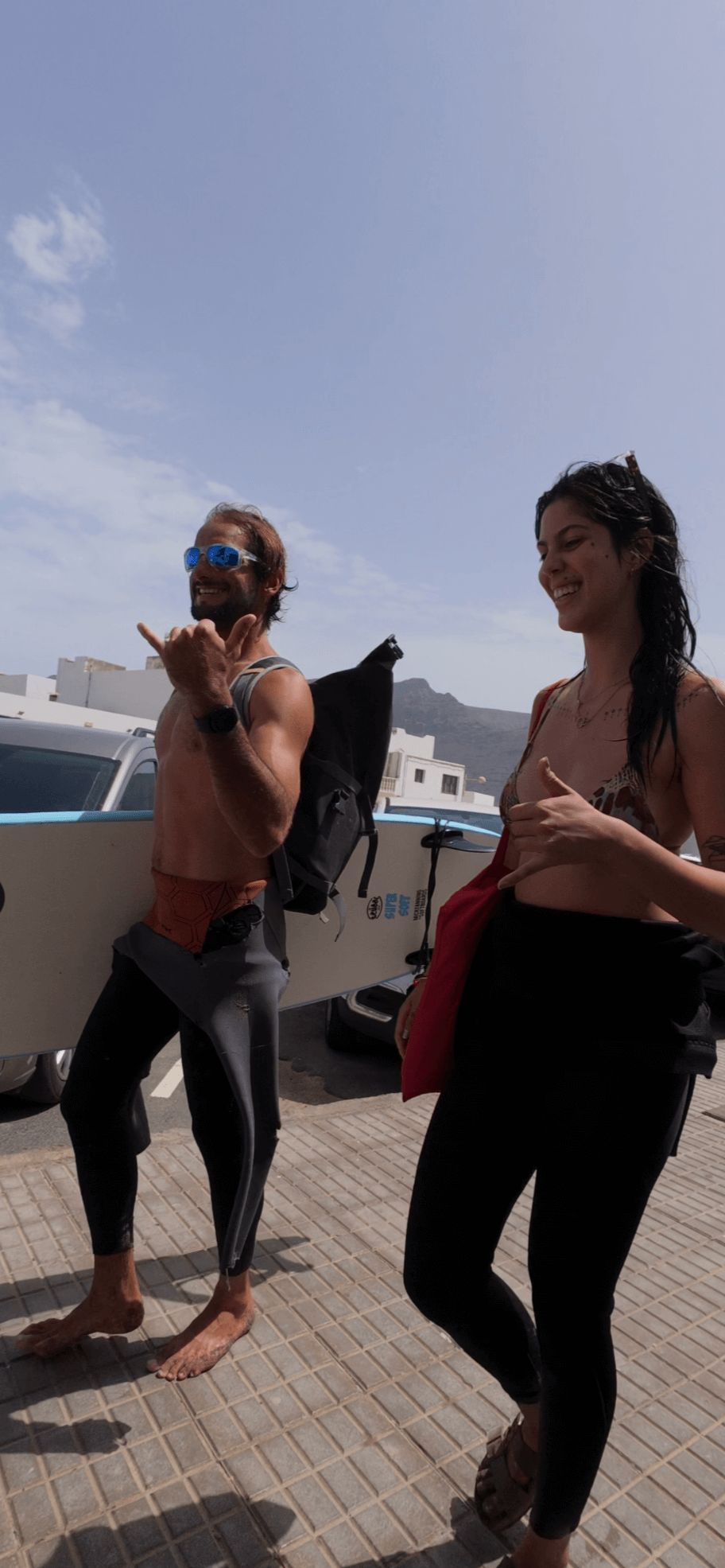 Two surfers in wetsuits gesturing with shaka signs before a private surf lesson at Lanzarote's Famara Beach