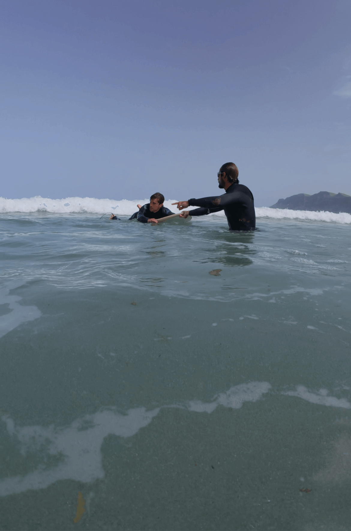 Surf lesson with instructor coaching a beginner in small group at Famara Beach, Lanzarote