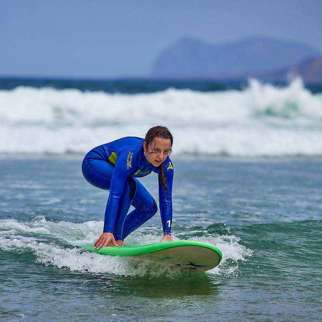 Young surfer catching a wave during a small group surf lesson at Famara Beach, Lanzarote